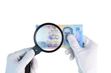 Investigeting counterfeit money. Hands in white gloves with magnifier holding 50 baht bill isolated on white background.