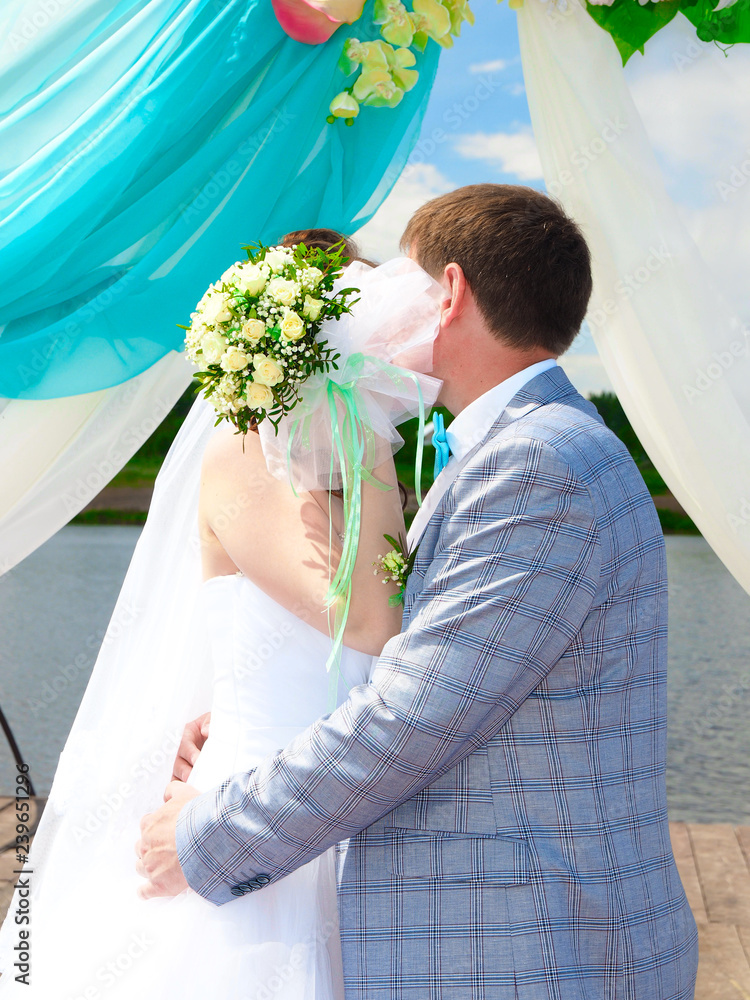 Wall mural Wedding. Newlyweds kiss under a wedding arch