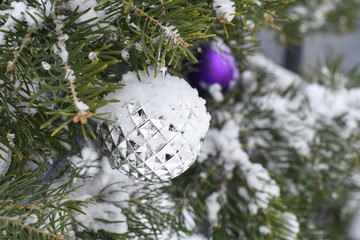 Christmas decoration on fir tree covered with snow. Christmas ornaments on branch outside
