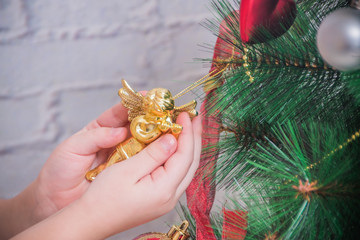 girl, child decorates Christmas tree on white brick wall background
