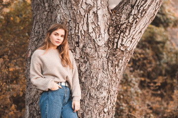 Beautiful teen girl 16-17 year old wearing stylish clothes posing outdoors. Lookng at camera. 20s.