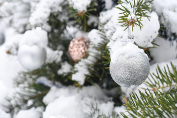 Fototapeta na wymiar Christmas decoration on fir tree covered with snow. Christmas ornaments on branch outside