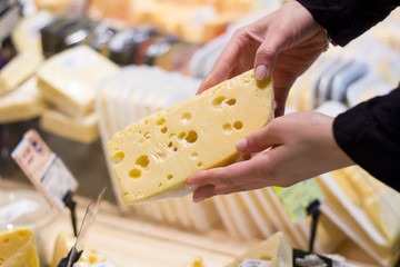 female hands holding cheese in a supermarket close-up