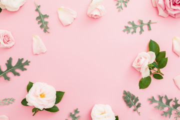 Floral frame made of roses and leaves on pastel pink background. Flat lay, top view.