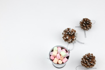 a small bucket with colorful marshmallows and pine cones on a white background. copy space. the view from the top. sweet additive in coffee. Children's sweetness.