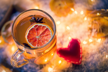 Heart shape and cup of tea with lemon on snow and fairy lights background