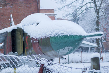 Military aircraft fighter exhibit covered in snow.