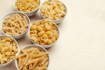Different pasta types in bowls on the table.