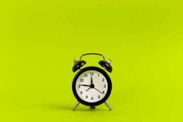 Vintage black alarm clock on a bright green background