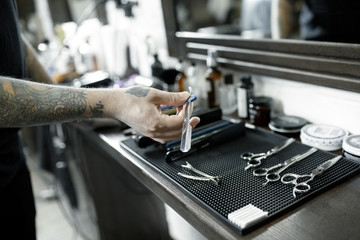 Fototapeta premium The male hands and tools for cutting beard at barbershop. Vintage tools of barber shop