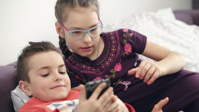 Children use smartphone at home. Close up kids looking modern modile phone