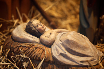 Jesuskind Figur aus Holz geschnitzt in Weihnachtskrippe auf Stroh an Weihnachten