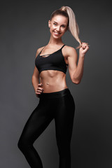 Fototapeta na wymiar Sports girl with pumped muscles,beauty body in a tracksuit, leading a healthy lifestyle and posing in the studio.