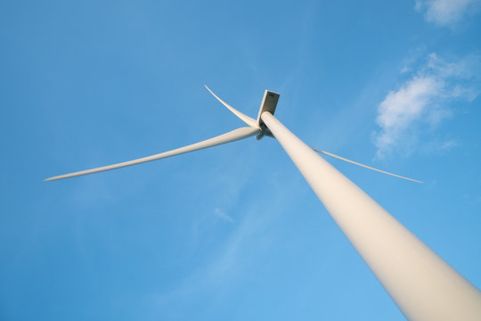 View up, bottom view of wind turbine, windmill isolated on blue sky background. Royalty high-quality free stock photo image looking up wind turbine, windmill energy converter in a blue sky background 