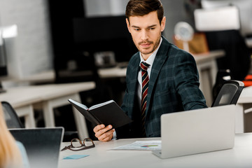 focused businessman with notebook working on laptop in office