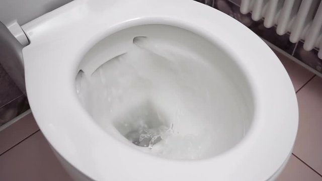 Flushing water in modern clean white rimless toilet. Closeup. Macro. Slow mo, slo mo, slow motion, high speed camera, 240fps, 250fps