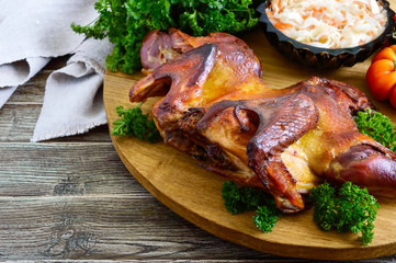Whole baked flattened chicken with a golden crispy crust with fresh vegetables, herbs and cabbage salad on a wooden tray. 
