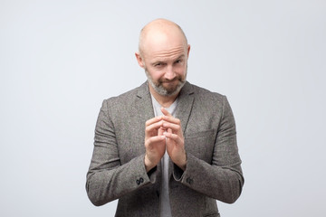Cunning tricky mature man thinking with hand together over white background. Concept of unfair game
