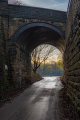 Fototapeta na wymiar brick arched bridge with power lines and glowing sun
