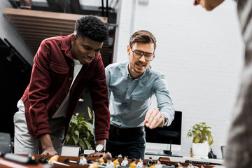 multiracial business colleagues playing table football together in office