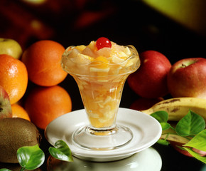 Una copa con zumo de naranja y macedonia de frutas.