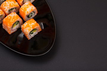 Uramaki California. Sushi rolls on a plate with black background.