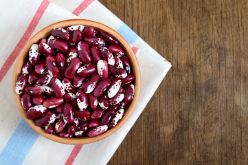 Red raw beans in bowl on a wooden table. Healthy food, dieting, nutrition concept. Legumes - vegan protein source.