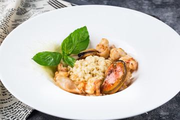Risotto with mussels on a white plate with basil. Healthy eating concept, Meditarranian life style