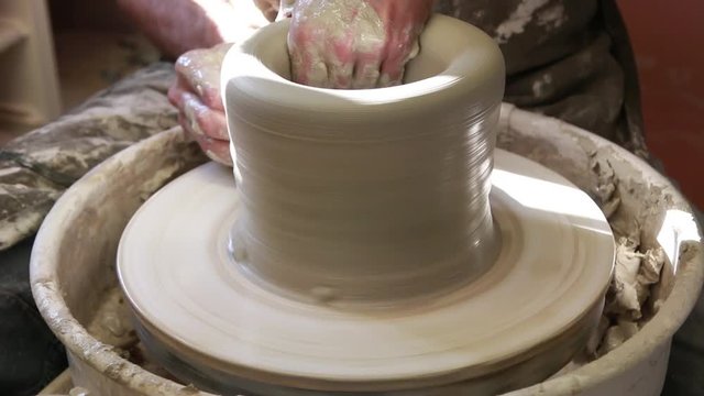     Artist potter in the workshop creating a ceramic vase. Hands closeup. Twisted potter's wheel. Small artistic craftsmen business concept. 