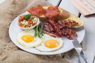Homemade delicious american breakfast with sunny side up fried egg, toast, sausage, vegetables.