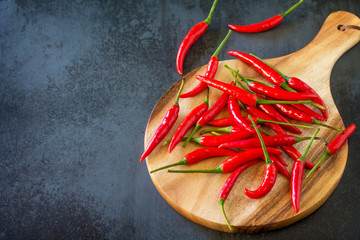 Red Hot Pepper Chili Peppers on a cutting wooden board, vintage stone background.