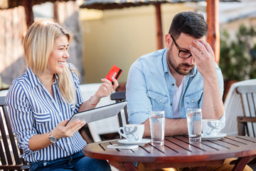 Young couple arguing over online shopping. Woman holding credit card and a tablet