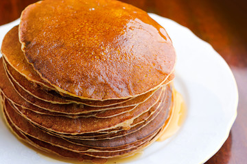Ruddy pancakes with honey on a dark background.