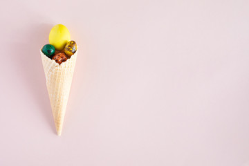 Happy Easter background with copy space. Colorful easter eggs in waffle cone on pink background