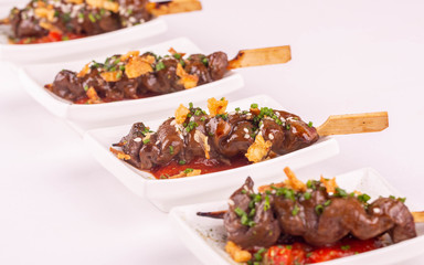 A beef shish kebab on a skewer in sauce with greens