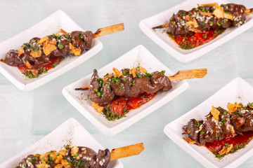 Beef on a grill, is served on a skewer under hot sauce