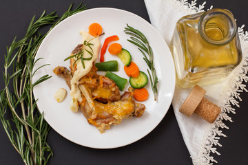Rabbit legs baked in white wine with bechamel sauce on a ceramic plate.