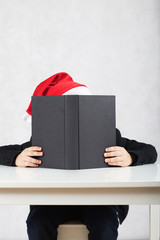 Boy in Santa's hat and black classical jacket. , Boy in Santa's hat and black book.