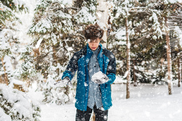 Fototapeta na wymiar young boy playing snowball and other winter activities on a snowy day in the park f