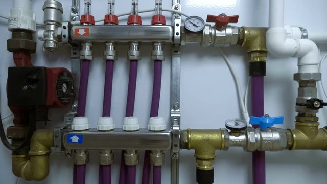 White box with a water distribution system in heated floors with pipes, taps, temperature gauges, an electric motor in a boiler room. Shot in motion