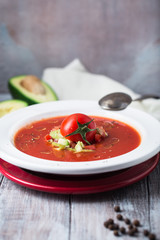 Cold summer tomato dish. Gaspacho soup with toast, cherry tomatoes, pepper, basil herbs, avocado