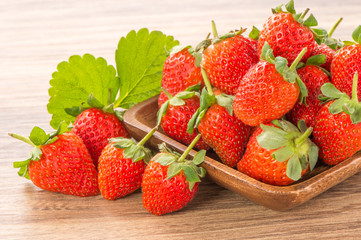 A plate of beautiful strawberries isolated on wooden background, close up, macro.