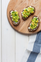 Avocado toast on a wood cutting board. Top view
