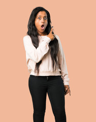 Young afro american woman surprised and pointing side on isolated brown background