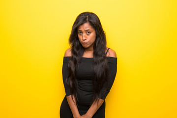 Naklejka premium Young afro american woman on vibrant yellow background with sad and depressed expression