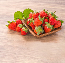 A plate of beautiful strawberries isolated on wooden background, close up, macro.