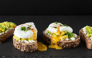 Toast with poached eggs, avocado on black background