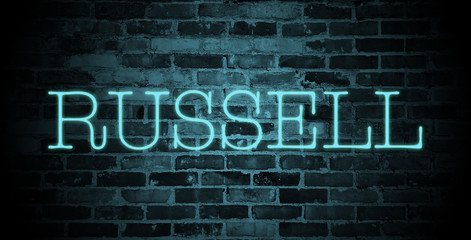 first name Russell in blue neon on brick wall