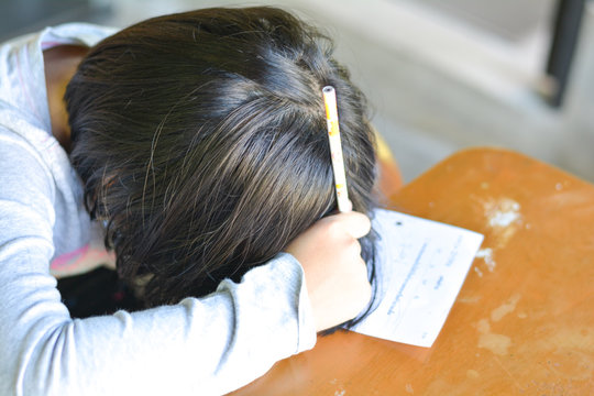 Attention deficit hyperactivity disorder (ADHD) and Learning disability (LD) in children and teens concept.Female cute child asleep on paper.Asian students sleeping while practice math subject at home