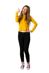 A full-length shot of a young girl with yellow sweater frustrated by a bad situation and pointing to the front on isolated white background